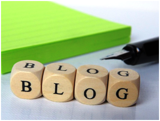 Wooden blocks spelling 'BLOG' next to a fountain pen and green notepad, symbolizing blogging and content creation.