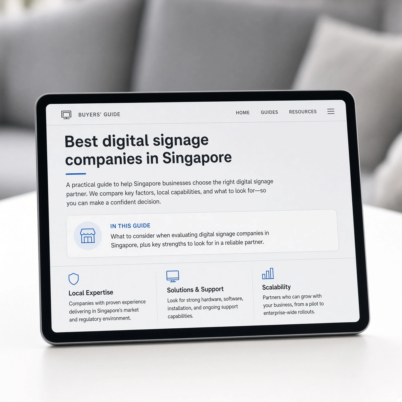 Tablet showing a Singapore digital signage companies buyers’ guide beside a modern lounge sofa