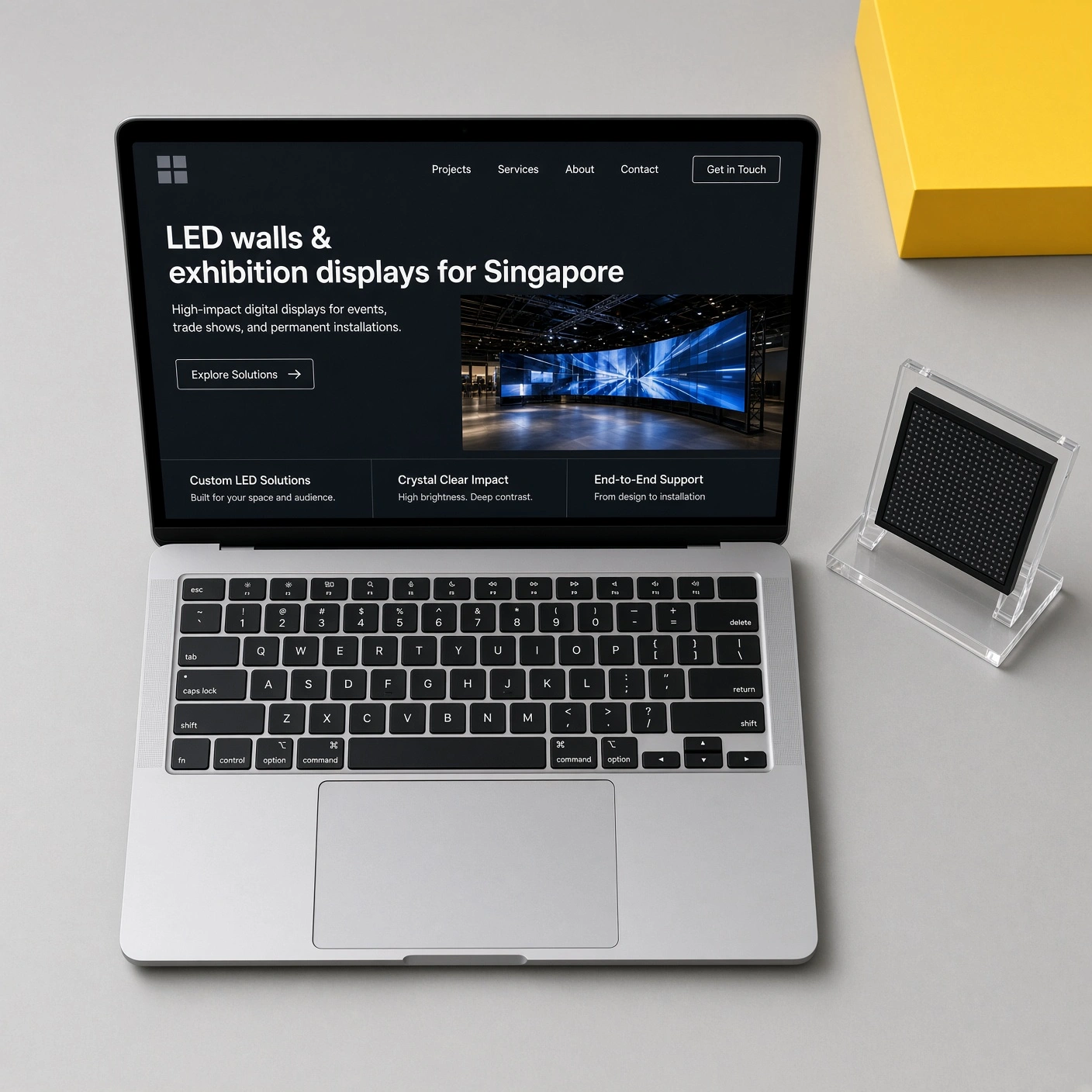 Laptop showing a Singapore digital signage and exhibition display website on a desk with a display sample