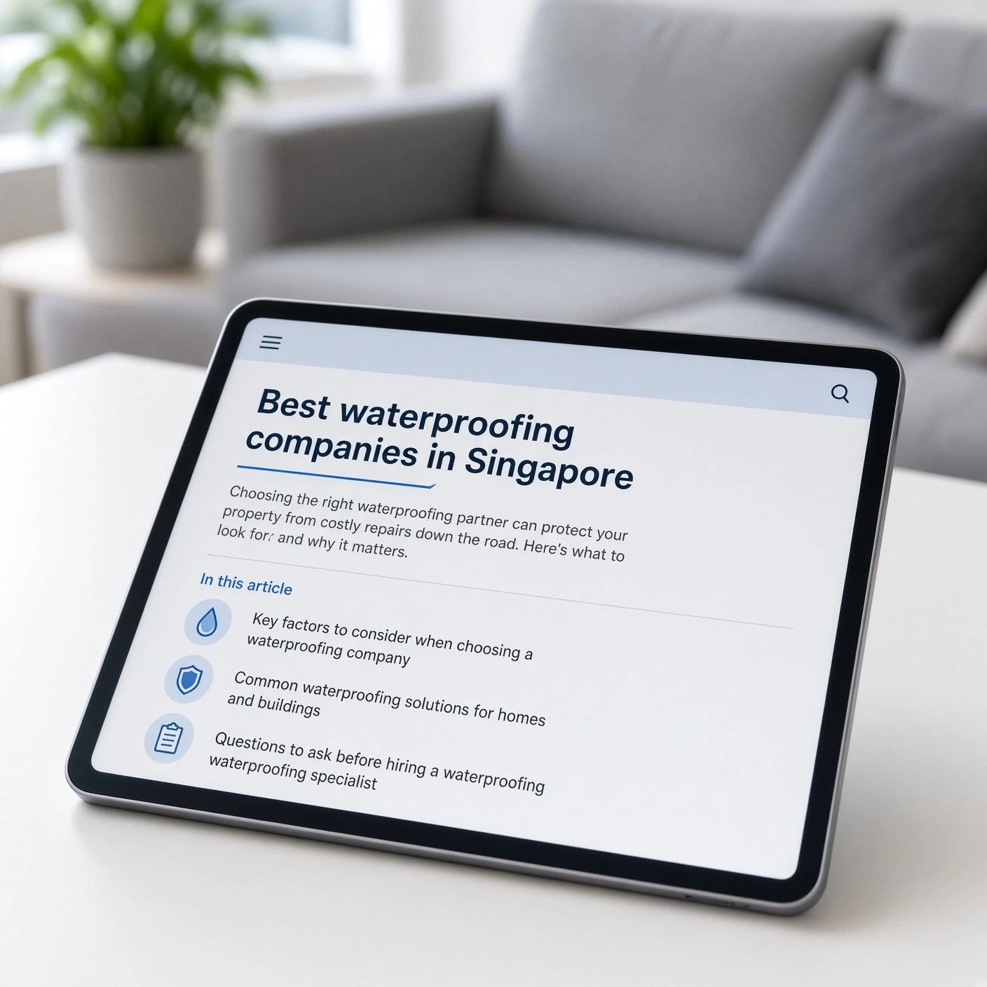 Tablet showing a Singapore waterproofing companies guide article beside a modern lounge sofa